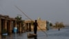A man rows his boat as he passes through flooded market, following rains and floods during the monsoon season in Bajara village, at the banks of Manchar lake, in Sehwan, Pakistan, Sept. 6, 2022. 