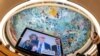 UN High Commissioner for Human Rights Volker Türk is seen on a TV monitor as the ceiling of the Human Rights and Alliance of Civilizations Room is seen in the background at the opening of the 53rd UN Human Rights Council in Geneva, June 19, 2023.