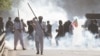 Supporters of former Prime Minister Imran Khan react amid tear gas smoke fired by the police to disperse them during clashes, in Lahore, Pakistan, March 8, 2023.