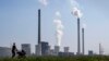 FILE - A mother pushes a stroller in front of the Scholven coal-fired power station, in Gelsenkirchen, Germany, March 28, 2022.