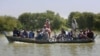 FILE - Villagers with their belongings cross a flooded area on a boat, in Dadu, a district of southern Sindh province, Pakistan, Sept. 23, 2022. 
