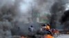 FILE - Motorcycle drivers pass through a burning road block as anger mounted over fuel shortages that have intensified as a result of gang violence, in Port-au-Prince, Haiti, July 13, 2022.