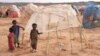 FILE - Children stand next to a makeshift shelter at the Higlo camp for people displaced by drought, in the town of Gode, in Ethiopia's Somali region, April 27, 2022. 