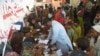 FILE - Families displaced by floods gather around a paramedic at a makeshift medical camp set in Dadu district, Sindh province in Pakistan on Sept. 27, 2022.