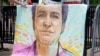 Un portrait de Marc Fogel qui était détenu en Russie depuis août 2021, accroché sur des barrières à l'extérieur de la Maison Blanche lors d'une manifestation organisée par sa famille, 15 juillet 2023. AP / Stephanie Scarbrough