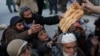 FILE - People reach out to receive bread, in Kabul, Afghanistan, Jan. 31, 2022. 