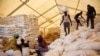 FILE: Men carry bags of food while women wait for their rations at the United Nations World Food Programme (WFP) food distribution site in Pibor, South Sudan, June 25, 2012.