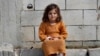 FILE - A displaced Syrian girl sits outside her family's tent at a refugee camp in Bar Elias, Bekaa Valley, Lebanon, March 5, 2021. 