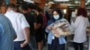 People queue as a woman carries several loafs of bread at a bakery in Beirut, Lebanon, June 29, 2022.