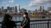Seorang wisatawan mengenakan masker saat berfoto dengan latar belakang Cincin Olimpiade di distrik Odaiba, Tokyo, 29 Januari 2020. (Foto: dok).