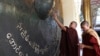 Two monks touch the large bronze gong at the Maha Muni Buddha Temple in Mandalay. (Z. Aung/VOA)