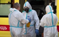 Un profesional médico con equipo protector contra el coronavirus desinfecta a sus colegas luego de llevar un paciente de COVID-19 en ambulancia a un hospital en San Petersburgo, Rusia, el jueves 1 de octubre de 2020.