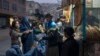 FILE - A man distributes bread to women outside a bakery in Kabul, Afghanistan, Dec. 2, 2021. 
