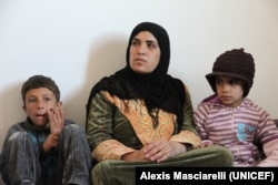 A Syrian woman at home with two of her children inside their apartment in the city of Mafraq, in Northern Jordan. Her husband has remained in Syria. Courtesy: UNICEF: Alexis Masciarelli