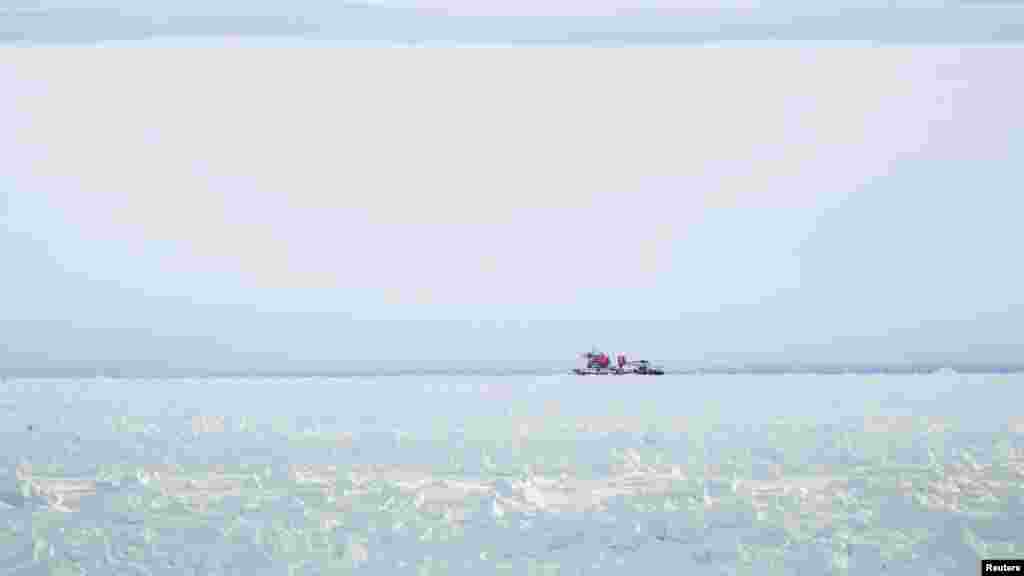 Kapal pemecah es Xue Long (Naga Salju) yang berada di atas tumpukan es tidak dapat mencapai kapal Rusia yang terperangkap di Antartika Timur, MV Akademik Shokalskiy, sekitar 185 kilometer sebelah timur stasiun Antartika Perancis Dumont D&#39;Urville.