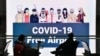 지난 17일 한국 인천국제공항에서 "COVID-19가 없는 공항"이 적힌 전광판 앞으로 마스크를 착용한 여행객들이 앉아 있다. 