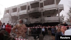 Warga berdiri diantara reruntuhan gedung di luar Kedutaan Besar Perancis di ibukota Libya, Tripoli, menyusul serangan bom di lokasi tersebut (23/4).