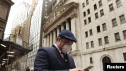 ARCHIVO - Un hombre usa una máscara protectora mientras pasa frente a la Bolsa de Valores de Nueva York, el 13 de marzo de 2020.