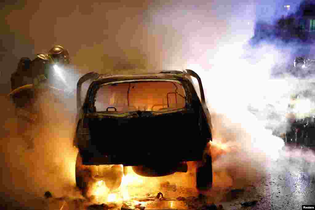 Petugas pemadam kebakaran memadamkan sebuah mobil yang terbakar dalam insiden perayaan tahun baru di kota Lille, Perancis. 