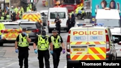 Representantes de las fuerzas de seguridad recorren la escena del crimen, una céntrica calle de la ciudad de Glasgow, Escocia.