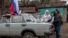 Члени місцевої виборчої комісії у супроводі військовослужбовця забезпечують голосування на пересувній виборчій дільниці під час виборів президента РФ-2024 в окупованому Росією українському Донецьку. STRINGER/AFP