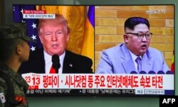 A South Korean soldier walks past a television screen showing pictures of US President Donald Trump (L) and North Korean leader Kim Jong Un at a railway station in Seoul on March 9, 2018.