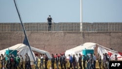 Inmigrantes rescatados de varias embarcaciones permanecen en el puerto de Arguineguin, donde son cuidados por la Cruz Roja y la Policía Nacional.