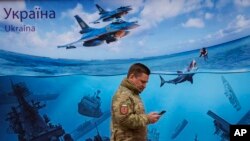 ФСБ заявила, що буцімто зірвала план британських спецпризначенців висадити українських диверсантів на Тендрівську косу в Чорному морі у Херсонській області. На фото український військовий проходить біля плаката української поштової марки із зображенням затонулих кораблів РФ.