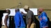 People look at results placed outside a polling station in Harare, Zimbabwe, July 31, 2018. 