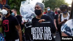 FILE - People participate in a demonstration on the first anniversary of the death of George Floyd, in Brooklyn, New York, May 25, 2021.