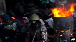 An opposition supporter warms himself next to a fire in a barricade near Kyiv's Independence Square, Jan. 31, 2014. 
