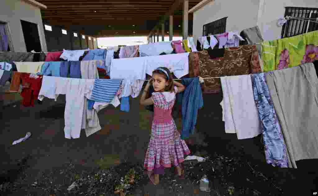 A Syrian girl, who fled her home with her family due to fighting between the Syrian army and the rebels, looks back while checking her laundry, near the Syrian town of Azaz, Aug. 26, 2012. 