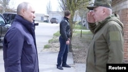 Президент России Владимир Путин слушает генерал-полковника Олега Макаревича, командующего группой войск «Днепр», во время его визита в штаб группы армий «Днепр» в Херсонской области, 18 апреля 2023 года.