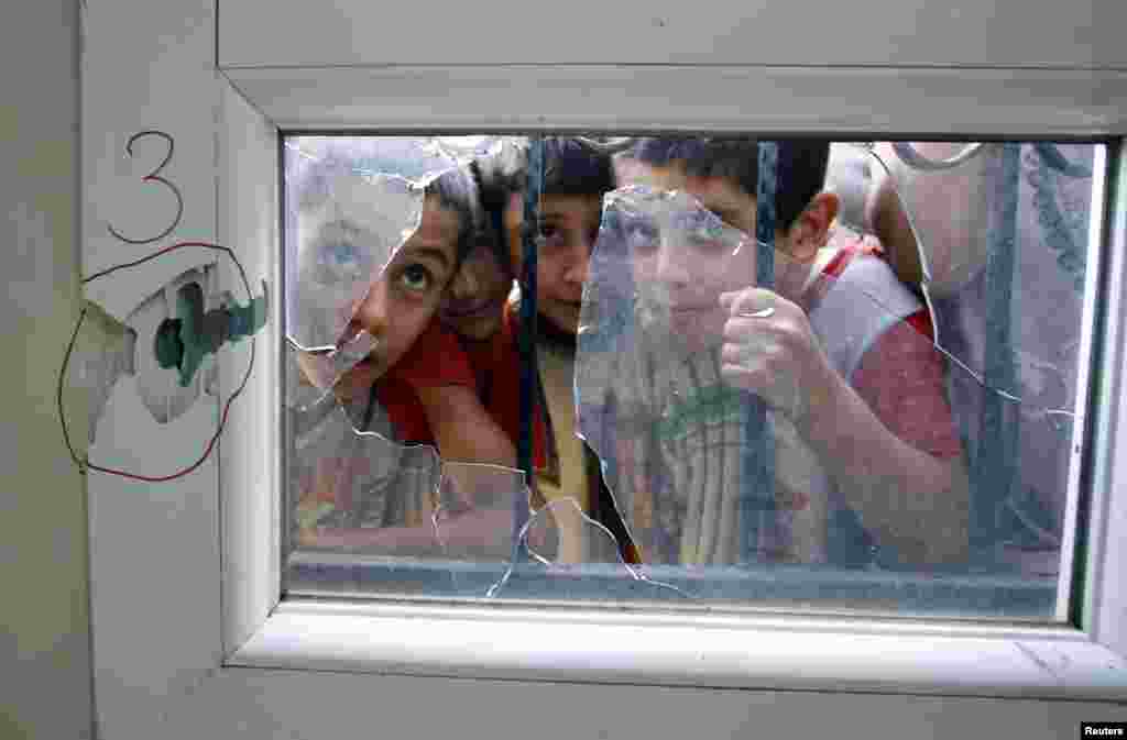 Turkish boys look through a shattered window after an anti-aircraft shell fired from Syria hit a health center across the border in Reyhanli, Hatay province, Turkey, October 23, 2012. 