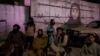 FILE - Taliban fighters sit in front of a mural depicting a woman behind barbed wire, in Kabul, Afghanistan, Sept. 21, 2021.