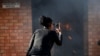 FILE - A women uses a cellphone to take pictures of a burning principal's school office in Mashau Dolly village in South Africa's northern Limpopo province, May 5, 2016. 