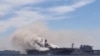 Un incendio en el buque de asalto anfibio de la Marina de los EE.UU. USS Bonhomme Richard en la Base Naval de San Diego, California, deja ver la nave rodeada por el humo en esta foto de redes sociales, el 12 de julio de 2020. [Foto: Charisma Emralino/via 