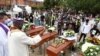 ARCHIVO - Un sacerdote con una máscara facial por la pandemia de coronavirus rocía agua bendita sobre los ataúdes durante el funeral de cinco menores que fueron asesinados en la ciudad de Cali, Colombia, 14 de agosto 2020.