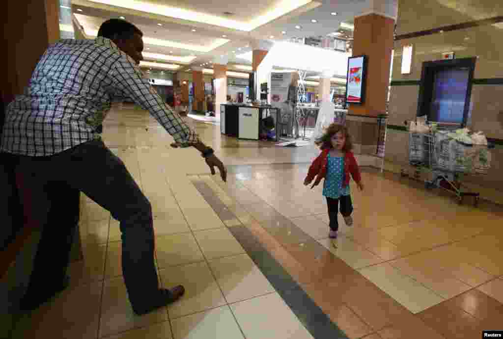 Seorang anak kecil berlari menyelamatkan diri saat polisi bersenjata mencari pria bersenjata yang menembaki pusat perbelanjaan di Nairobi, Kenya, 21 September 2013. Pria bersenjata keluar dari pusat perbelanjaan, membunuh paling tidak 20 orang dalam kejadian yang disebut sebagai serangan teroris oleh pemerintah.